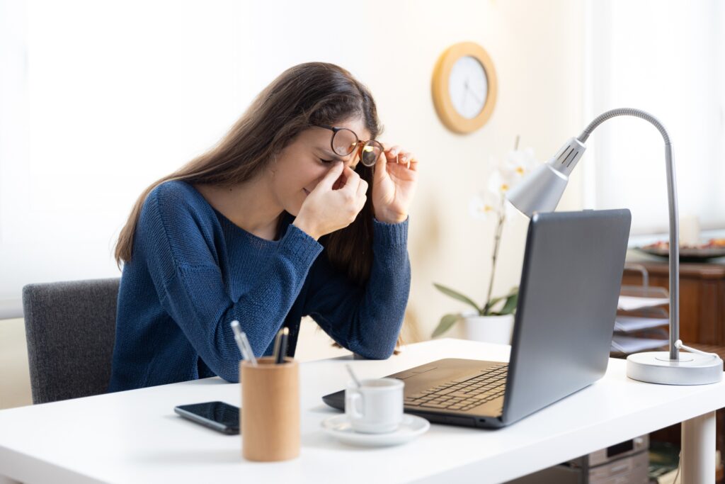 Leczenie migreny — kobieta z bólem głowy przy pracy